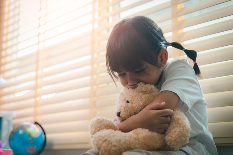 A close-up of a little girl hugging a stuffed animal.